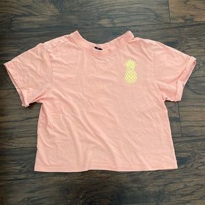 Salmon colored crop top with pineapple logo